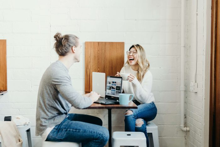 Man and woman conversing in an office over a laptop